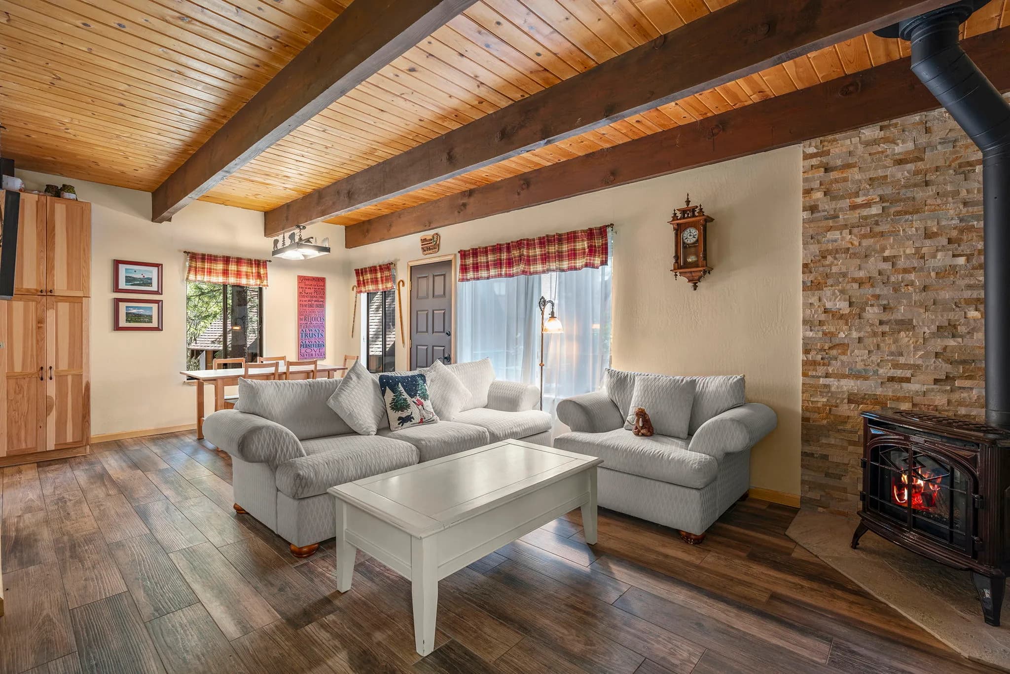 Open living room with exposed wood ceiling beams and a stone-surround gas stove at Fairway Park #34